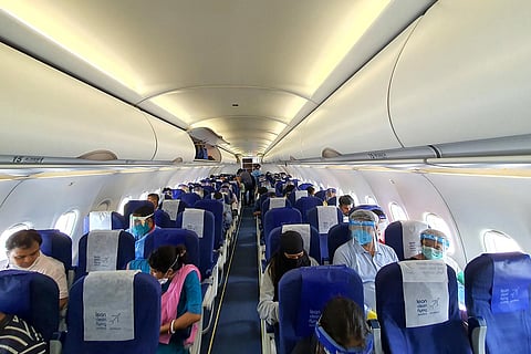 Passengers seated in a flight, Many are wearing face masks and shields