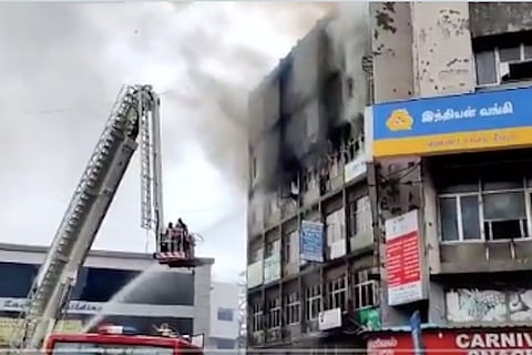 A crane placed next to a burning shopping complex 