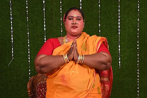 Ganga Nayak in a yellow and red saree with folded hands