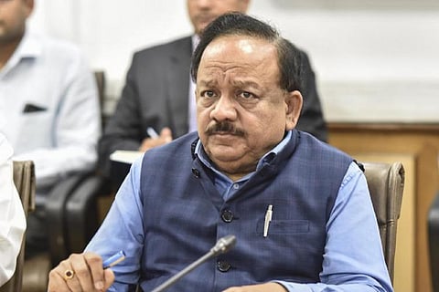 Harsh Vardhan sits before a microphone 