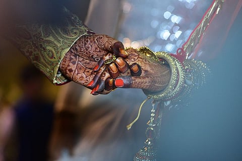 Image of two people holding mehendi-decked hands during a wedding