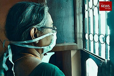 A woman wearing a mask and looking out a window