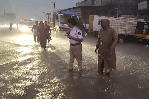Traffic police personnel standing on waterlogged roads during Hyderabad rains
