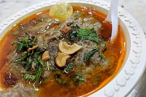 A plate of Haleem garnished with fried onion, cashews and onion 