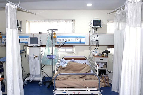 An ICU bed in an Indian hospital with a patient sleeping on his side 