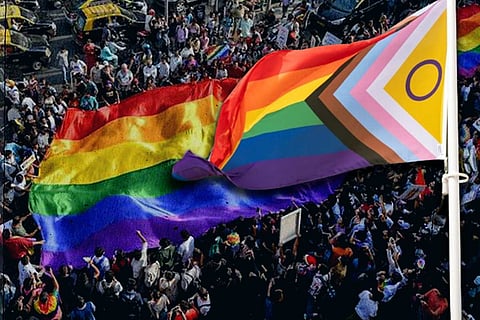 A rainbow flag with a pride march background