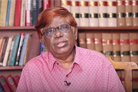 Justice Chandru wearing a pink shirt and facing the camera