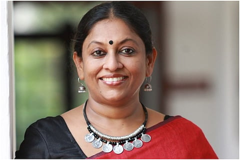 Kerala Writer KR Meera in a maroon saree smiling for camera 