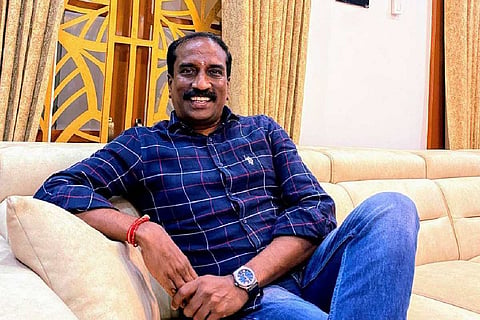 KR Venkatesh wearing a blue colored checked shirt and blue jeans, sitting on a sofa