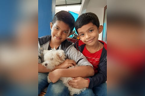 Sephan and Sayon are seeing holding Lucky, their pet dog, and smiling 