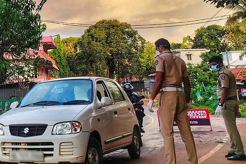 Two Kerala policemen stopping a car on a road 