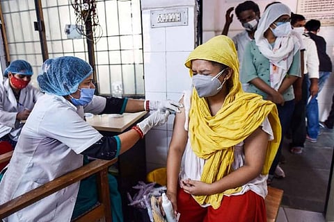 A health worker administers COVID-19 vaccine to a woman