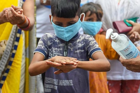 A boy in a blue t-shirt using sanitiser