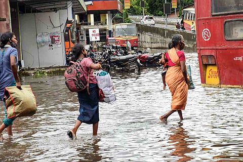 People walking through a waterlogged road in Kochi: Red alert sounded in five districts in Kerala, NDRF teams deployed