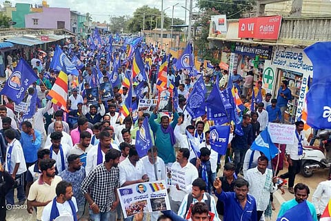 Protesters waving blue flags and banners as part of a massive protest in Kolar's Ullerahalli
