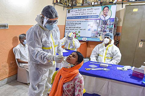 A health worker in a PPE suit collecting nasal swab sa,ple from a woman for coronavirus test