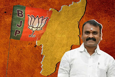 BJP leader and Union Minister of State L Murugan in a white shirt, Tamil Nadu map, BJP flag and a lotus symbol can be seen behind