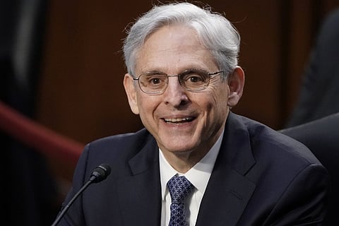 Merrick Garland in a black suit, tie and spectacles smiling 