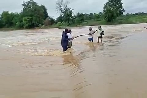 Two men being rescued during heavy rains and flood near Mulugu in Telangana