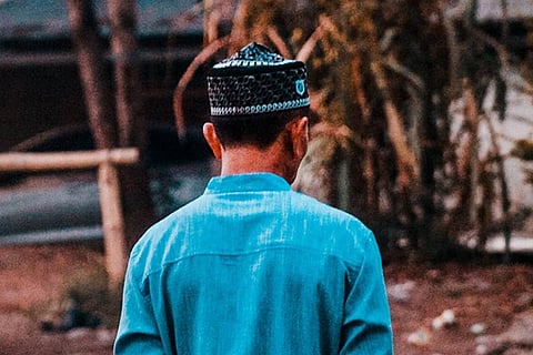 Muslim man in blue with back to camera
