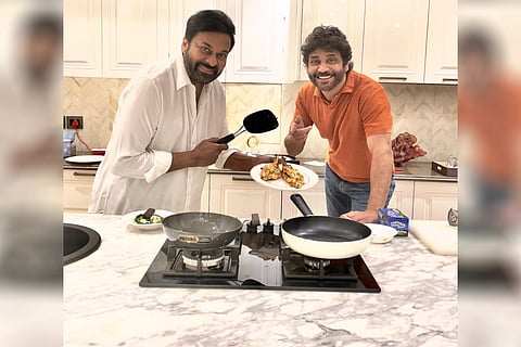 Chiranjeevi is seen holding a spatula in his hand and the chicken he cooked in the photo, while Nagarjuna can be seen pointing towards the scrumptious dish.