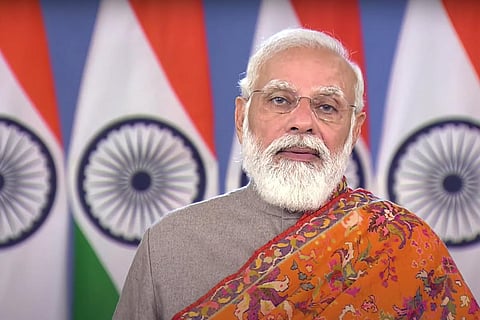 PM Modi standing in front of Indian flags
