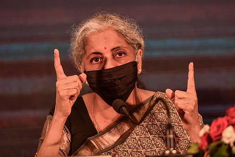 Nirmala Sithararam raises her two index fingers as she speaks wearing a black mask