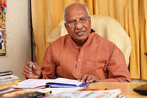 Kerala BJP MLA Rajagopal in a saffron color shirt, sitting on a chair and holding a pen in his hand