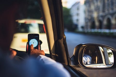 Representative image of a cab driver checking his mobile phone while seated in the cab