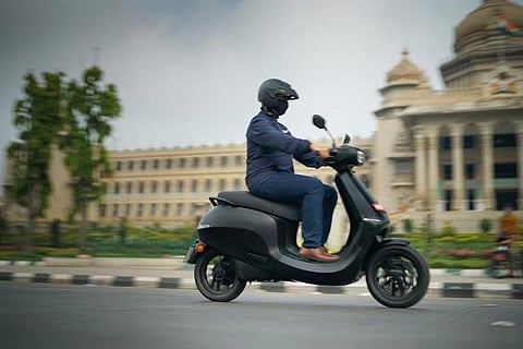 A person riding an Ola electric scooter