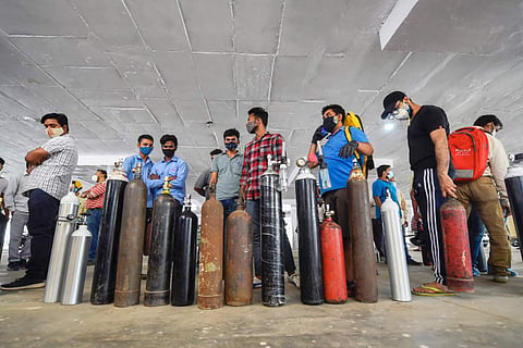 People standing in queue with oxygen cylinders