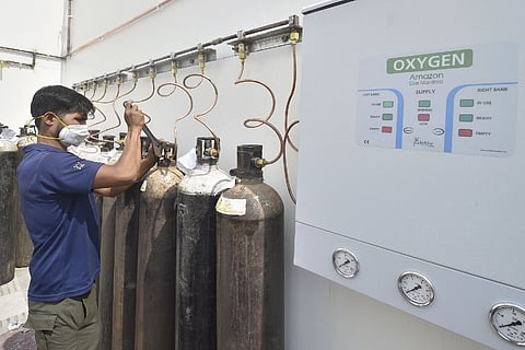 A man fixing an oxygen cylinder, he is wearing a mask
