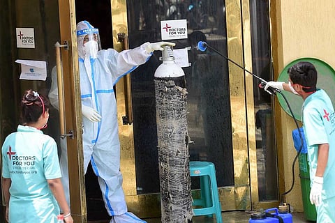 Health workers sanitise an oxygen cylinder at Shehnai Banquet, temporarily converted into COVID-19 isolation centre amid a surge in cases, in New Delhi