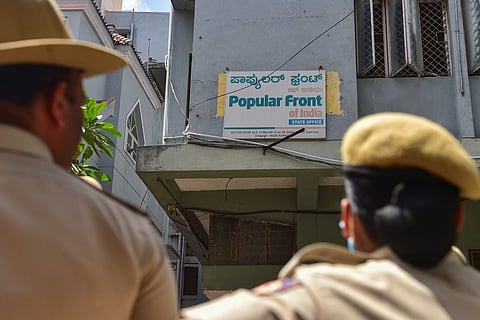 Police officials looking at the signboard of a Popular Front of India (PFI) office