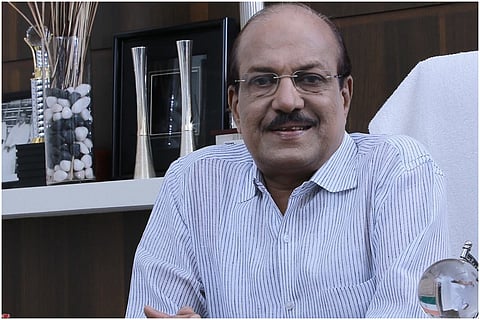 IUML Leader PK Kunhalikutty wearing white check shirt, smiling into camera 