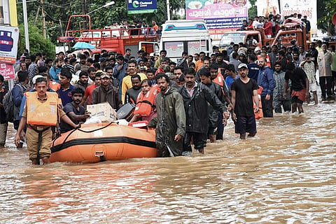 Several people pulling an inflatable raft through a flooded street in Kerala's Kochi
