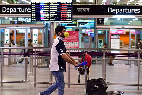 A man wheeling his luggage in front of him at an airport in India