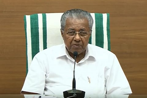 Kerala Chief Minister Pinarayi Vijayan addressing media sitting in a chair 