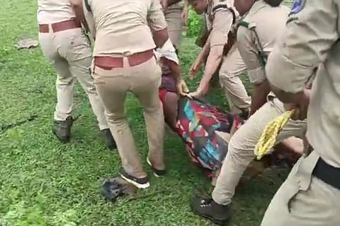 A woman being dragged by the forest department staff