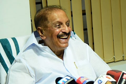 Kerala Congress leader R Balakrishna Pillai laughing while addressing media, with media mikes put in front of him