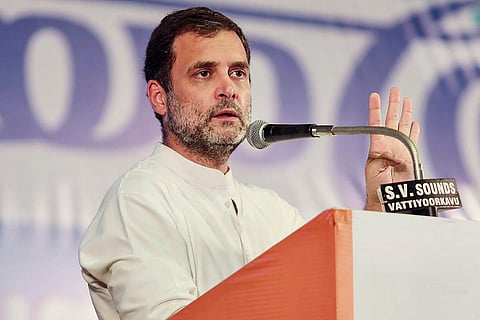 Rahul Gandhi clad in a white shirt, speaking at an event