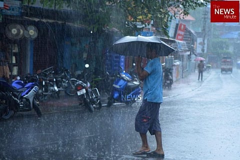 A man walking across a street holding a black umbrella in the rain