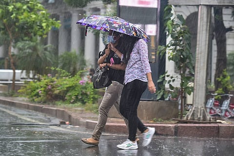 Two women walking in the rain with an umbrella