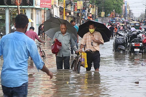 People wading through a flooded street after heavy rains