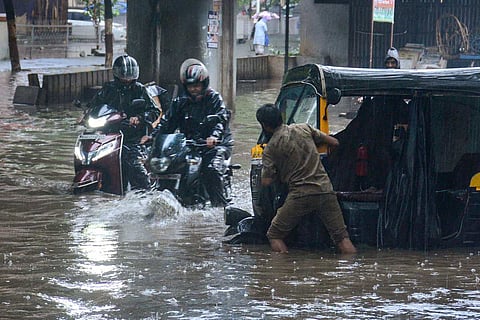 Representative image of a man pushing his autorickshaw through inundated streets