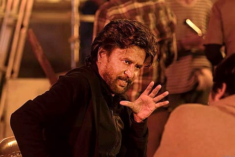 Rajinikanth in black and holding his hand up in Petta still 