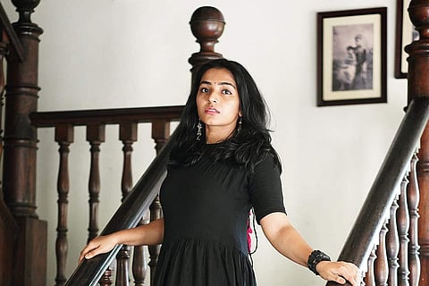 Rajisha Vijayan in a black dress standing on the stairs