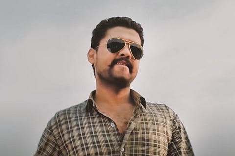 Rakshit Shetty in a plaid brown shirt in a still from the film Richie