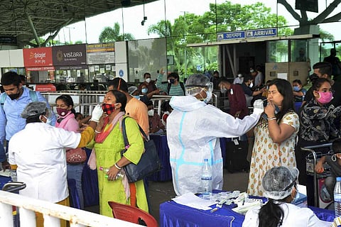 Health workers collecting nasal swabs of passengers outside an airport