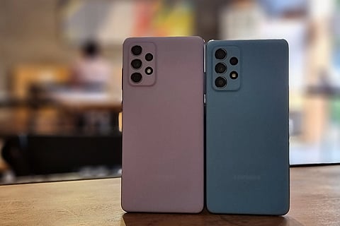 Back of two phones made to stand side by side on a table, one is violet in colour and one is blue in colour